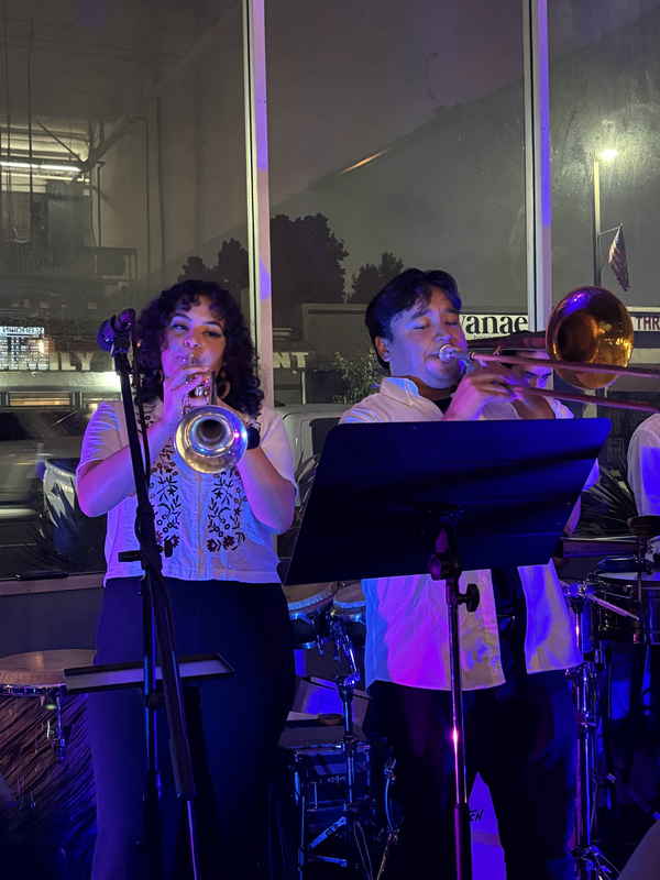 Two of our trumpet players in our Latin jazz band for events playing alongside one another as purple LED light shines on them | Altus Entertainment